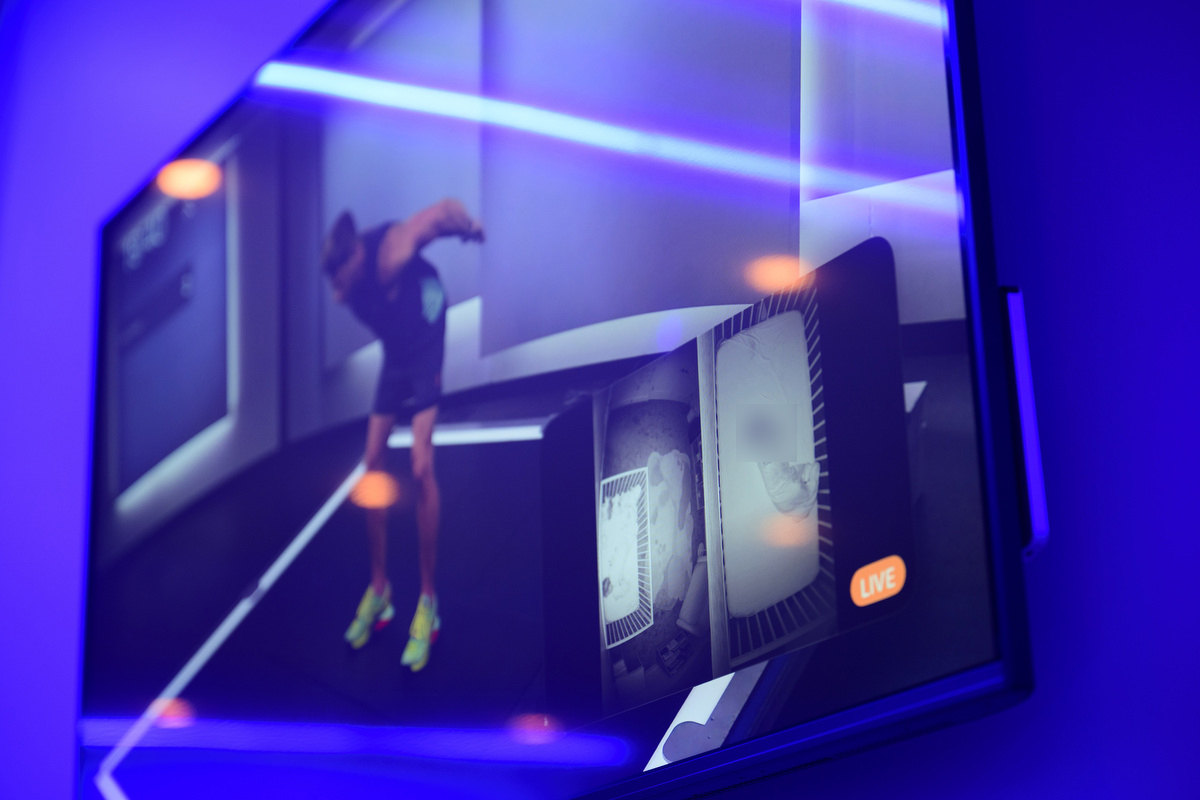 A picture-in-picture feed of two baby monitors is displayed in the bottom right hand corner of a tv screen. There is dramatic blue lighting in the room.