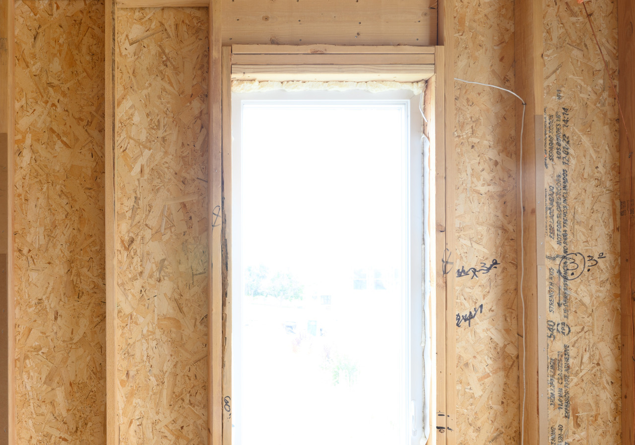 Shade wiring runs through exposed framing to the upper-right corner of a window during construction.
